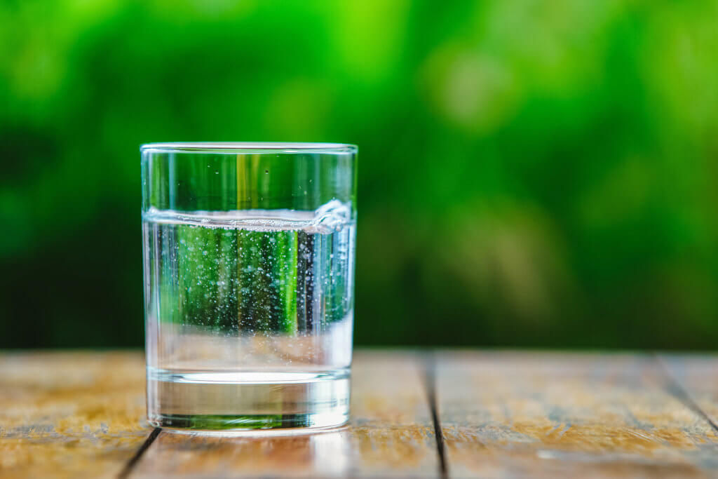 a,glass,of,water,on,green,background.,the,wooden,table.